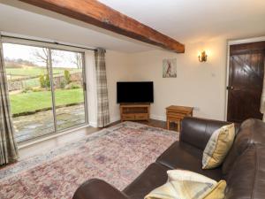 a living room with a couch and a flat screen tv at Dale View Cottage in Bakewell