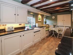 a large kitchen with white cabinets and a table at Dale View Cottage in Bakewell