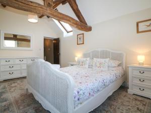 a white bedroom with a white bed and white dressers at Dale View Cottage in Bakewell