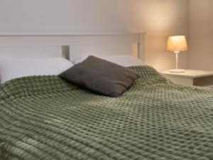 a green bed with a pillow on top of it at Panoramic Apartment in Odorheiu Secuiesc