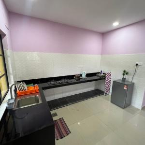 cocina con paredes de color púrpura y blanco y fogones en D` Totok HouseStay, en Sepang