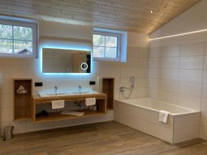 un bagno con vasca e lavandino di das MARX - Gasthof Marx - Apartments a Grosskirchheim