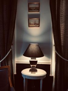 a lamp on a table in a room with curtains at Manoir du Clap in La Cerlangue