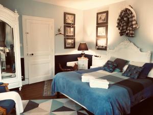 una camera da letto con un grande letto con una coperta blu di Manoir du Clap a La Cerlangue