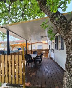 a wooden deck with a table and chairs and a tree at Kamp Slanik Mobile Homes in Umag
