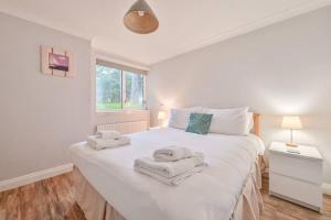 a bedroom with a large white bed with towels on it at Superb Sandbanks Apartment near Beach and Bars with Free Parking in Poole