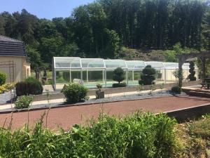 a greenhouse in a garden with trees in the background at DOMAINE du MOULIN in Saint-Avold