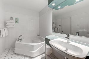 La salle de bains blanche est pourvue d'une baignoire et d'un lavabo. dans l'établissement Auberge La Chouette, à Québec
