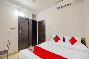 1 dormitorio con 1 cama grande con almohadas rojas en OYO Flagship 81047 Hotel Dream Inn, en Gamhāria