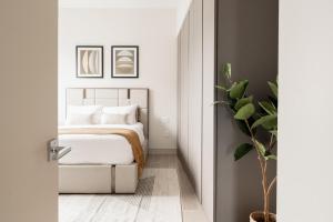 a white bedroom with a bed and a plant at City Views! - Chic Jefferson Park Condo - Tesoro in Denver