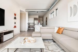 uma sala de estar com um sofá branco e uma mesa em Brand New Condo - Walk to Empower Stadium - Tesoro em Denver