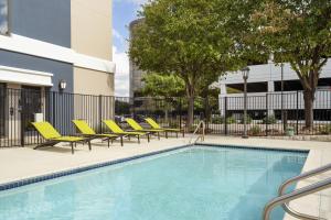 SpringHill Suites Fort Worth University في فورت وورث: مسبح وكراسي صالة صفراء بجانب مبنى