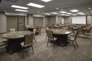 SpringHill Suites Fort Worth University في فورت وورث: قاعة اجتماعات مع طاولات وكراسي وطاولة بيضاء