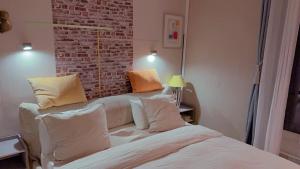Cette chambre comprend un lit avec des oreillers et un mur en briques. dans l'établissement Cozy Paris Apartment, à Paris