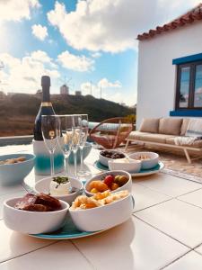una mesa con un plato de comida y copas de vino en Casinhas Fim do Mundo, en Reguengo Grande