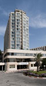 um grande edifício com uma palmeira em frente em Shalom Jerusalem Hotel em Jerusalém