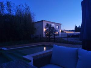 eine Couch, die nachts neben einem Pool sitzt in der Unterkunft Grande maison familiale avec piscine proche Avignon in Bagnols-sur-Cèze