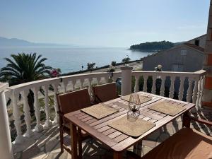a wooden table on a balcony with a view of the ocean at Apartmani Pavlović in Sućuraj