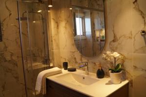 a bathroom with a sink and a shower with a mirror at Daphne Luxury Apartment in Kastoria