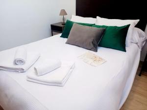 a white bed with white towels and green pillows at VIVAL MINAS in Baeza