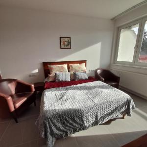 een slaapkamer met een bed, een stoel en een raam bij Demizson Panzió in Kehidakustány