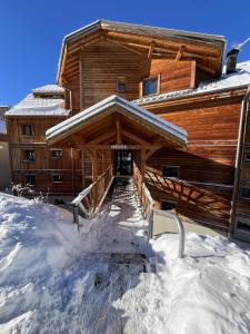 uma cabana com neve em frente em Studio cosy et moderne aux pieds des pistes em LʼHuez