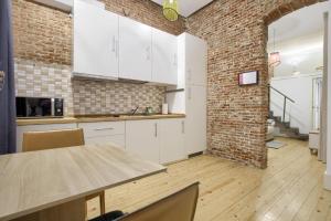 a kitchen with white cabinets and a brick wall at Charming Madrid Embajadores - Estancias Temporales in Madrid