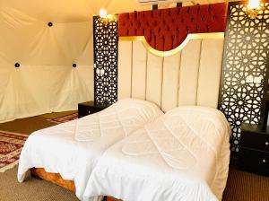 a bed in a room with a white bedspread at Hasan Zawaideh luxury camp 2 in Wadi Rum