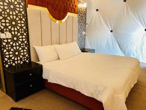 a bedroom with a large bed with a white bedspread at Hasan Zawaideh luxury camp 2 in Wadi Rum