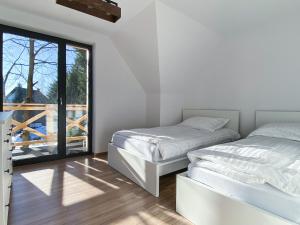 two beds in a white room with a window at Jankówki - Dom w górach in Nowy Targ