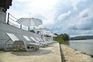 a row of white chairs and umbrellas next to a river at Banja na Drini - Lux vikendice na obali reke in Banja Koviljača