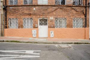 波哥大的住宿－Samor centro histórico Bogota，街道上一扇白色门的砖砌建筑