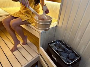 a girl is sitting on a bench in a sauna at Jacuzzi Loft & Sauna Sanctuary in Katowice