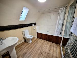 a bathroom with a toilet and a sink and a bath tub at George Hotel & Granary in Frome