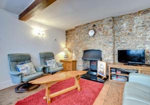 a living room with two chairs and a stone wall at Bosuns Cottage in Torquay