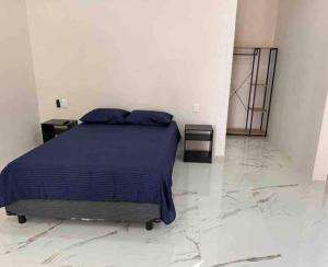een slaapkamer met een bed met blauwe lakens en marmeren vloeren bij Apartamento confortable y bien ubicado in Santa Cruz Huatulco