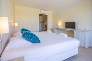 sypialnia z białym łóżkiem i niebieską poduszką w obiekcie Estalagem Muchaxo Hotel w mieście Cascais