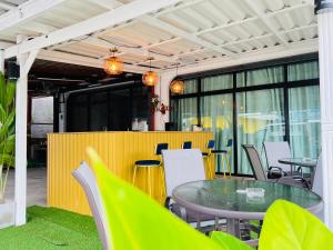 un patio al aire libre con mesa, sillas y ventanas en Jasper Phangan Hostel, en Thong Sala