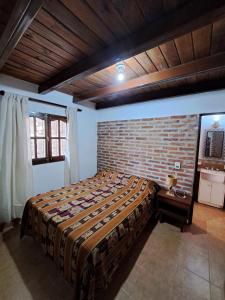 um quarto com uma cama e uma parede de tijolos em Kurpachana cómodos departamentos a 3 cuadras de la plaza. em Tilcara