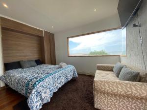 um quarto com uma cama, uma janela e um sofá em Hermosa Cabaña Rustica en Playa Negra em Concón