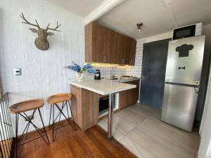 uma cozinha com um frigorífico e um balcão com bancos em Hermosa Cabaña Rustica en Playa Negra em Concón