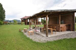 a pavilion with tables and chairs in a field at Banja na Drini - Lux vikendice na obali reke in Banja Koviljača