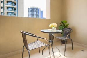 a table with two chairs and a table with flowers on it at Elite LUX Holiday Homes - Fabulous Studio in Dubai Marina in Dubai