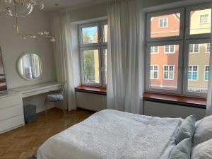 1 dormitorio con 1 cama, 2 ventanas y espejo en Apartament w centrum Gdańska en Gdansk