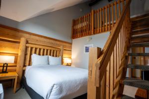 a bedroom with a bed and a staircase at Basecamp Lodge Golden in Golden