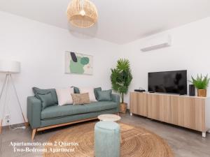 ein Wohnzimmer mit einem grünen Sofa und einem TV in der Unterkunft Akisol Albufeira Breezy in Olhos de Água