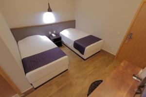 two beds in a small room with a wooden floor at Adria Premium Hotel in Guarapuava