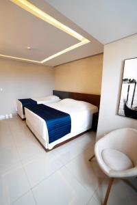 Un dormitorio con 2 camas y una silla. en Adria Premium Hotel en Guarapuava