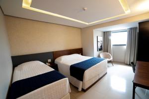 Habitación de hotel con 2 camas y escritorio en Adria Premium Hotel en Guarapuava