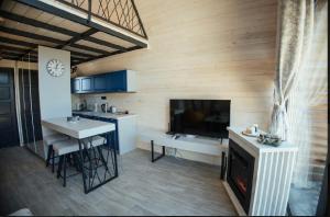 a kitchen with a living room with a fireplace and a tv at Sirius Lux Apartmani in Žabljak